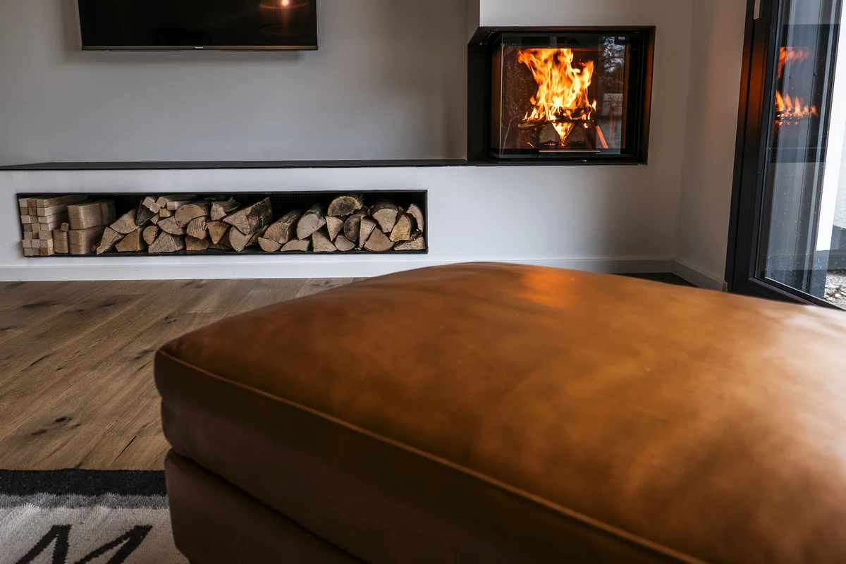 Heizkamin mit Ofenbank aus Naturstein und Regalfächern aus Stahl